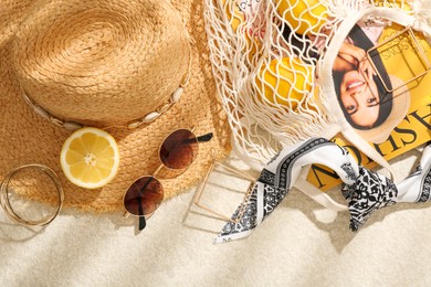 Photo of String bag with fashion magazine, fresh lemons and accessories on beige textured background, flat lay