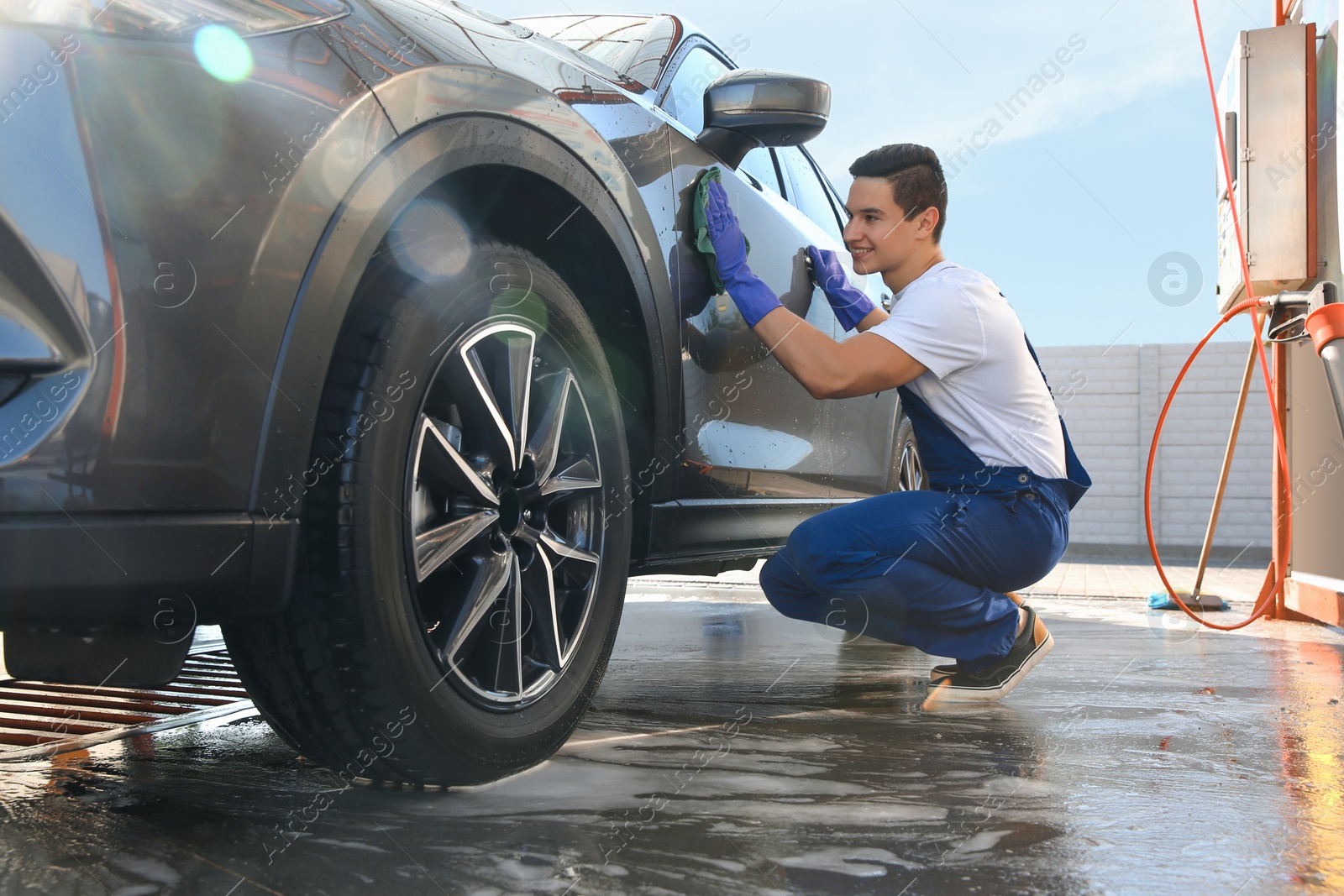 Photo of Male worker cleaning automobile door with rag at car wash