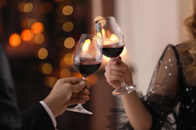 Photo of Couple clinking glasses at Valentine's day dinner in restaurant, closeup