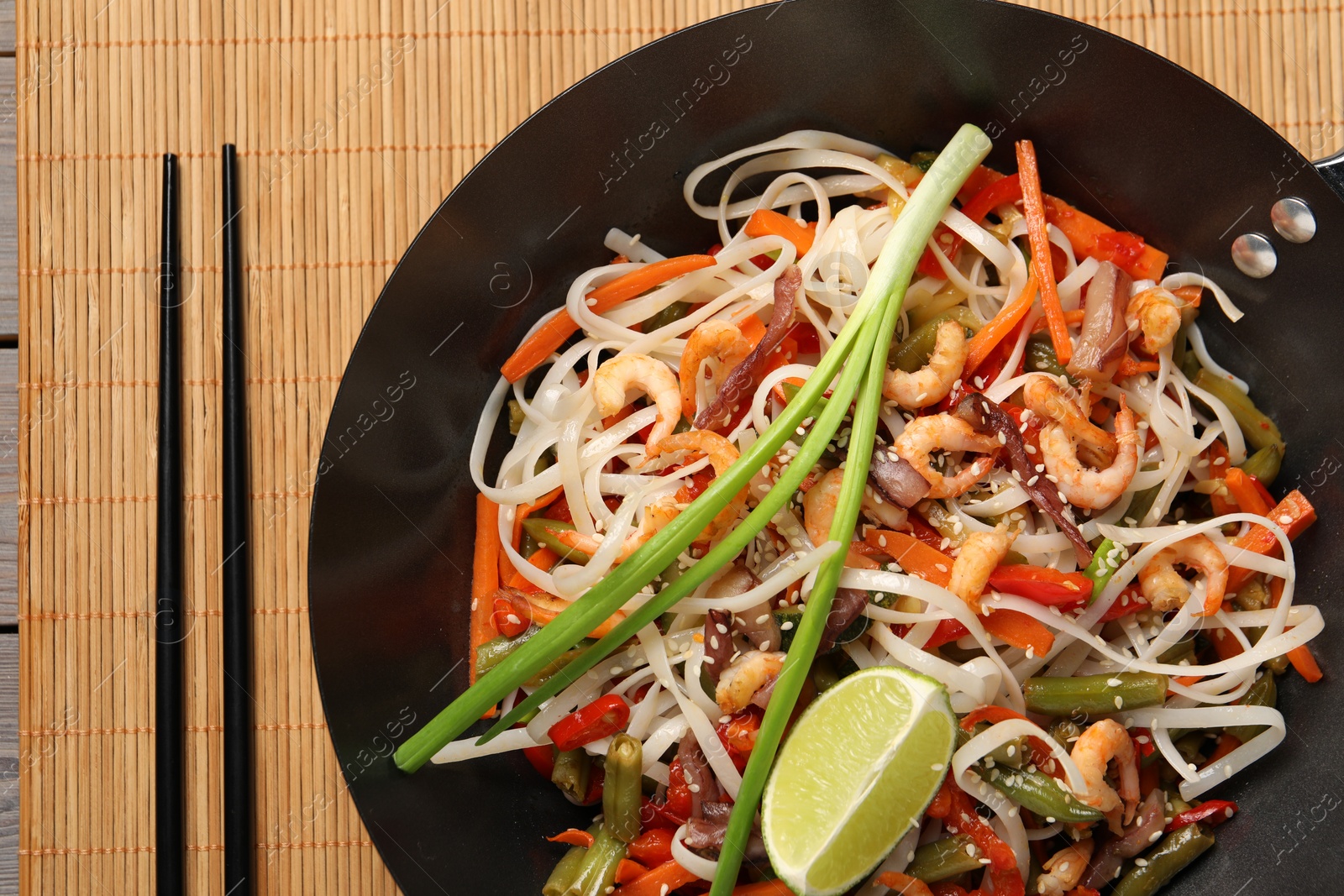 Photo of Shrimp stir fry with noodles and vegetables in wok on table