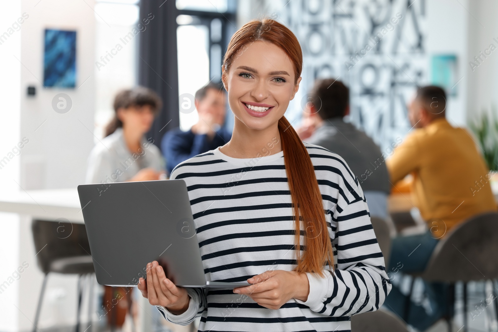 Photo of Team of employees working together in office. Happy woman with laptop indoors