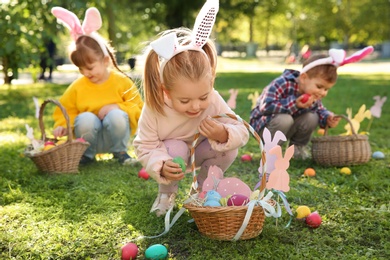 Cute little children hunting eggs in park. Easter tradition