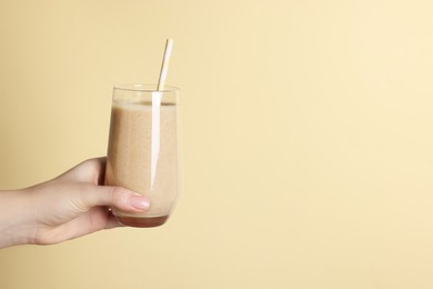 Photo of Woman holding glass of tasty smoothie on yellow background, closeup. Space for text