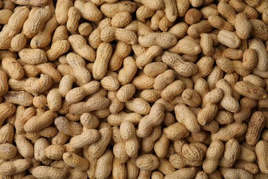 Many fresh unpeeled peanuts as background, top view