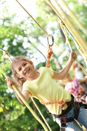 Little girl climbing in adventure park. Summer camp