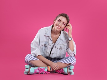 Young woman with retro roller skates on color background