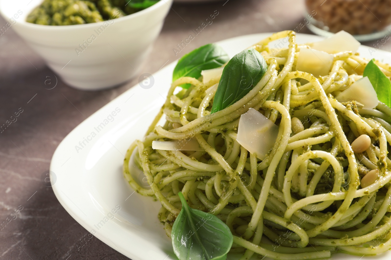 Photo of Plate with delicious basil pesto pasta on gray table