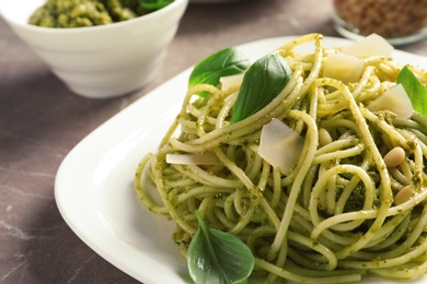 Plate with delicious basil pesto pasta on gray table