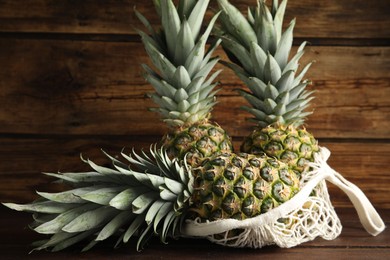 Photo of Bag with fresh juicy pineapples on wooden table, closeup