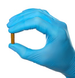 Photo of Scientist in protective gloves holding pill on white background, closeup