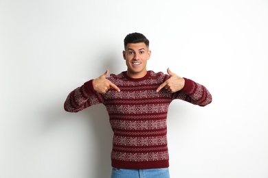 Man pointing on his Christmas sweater against white background