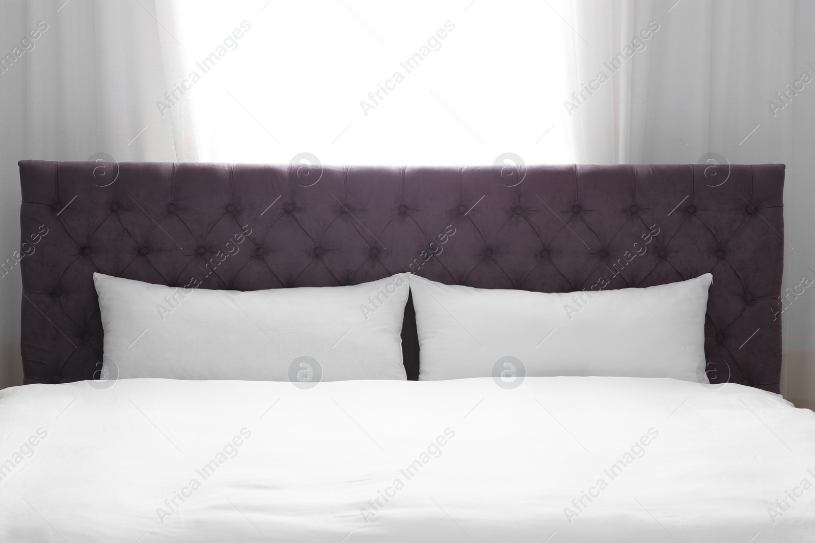 Photo of Modern bed with soft pillows near window