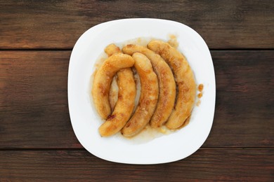 Photo of Plate with delicious fried bananas on wooden table, top view