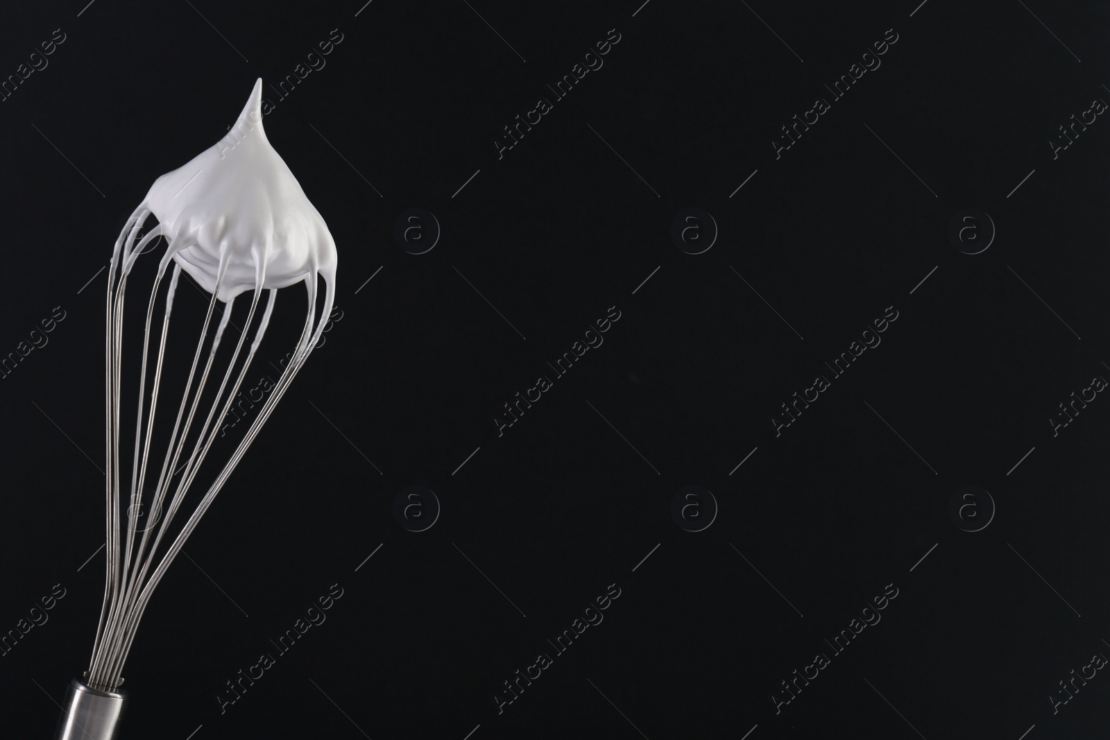 Photo of Whisk with whipped cream on black background. Space for text