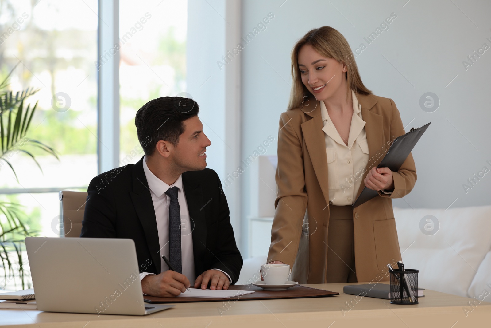 Photo of Secretary bringing coffee to her boss in office