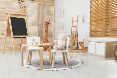Photo of Child's room interior with stylish table, chairs and toys