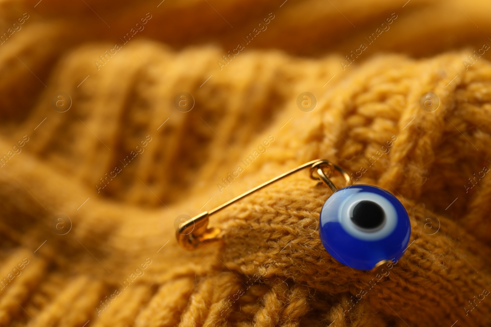 Photo of Evil eye safety pin on knitted clothing, closeup