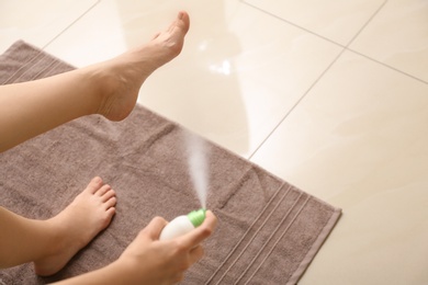 Young woman using foot deodorant at home, closeup. Space for text