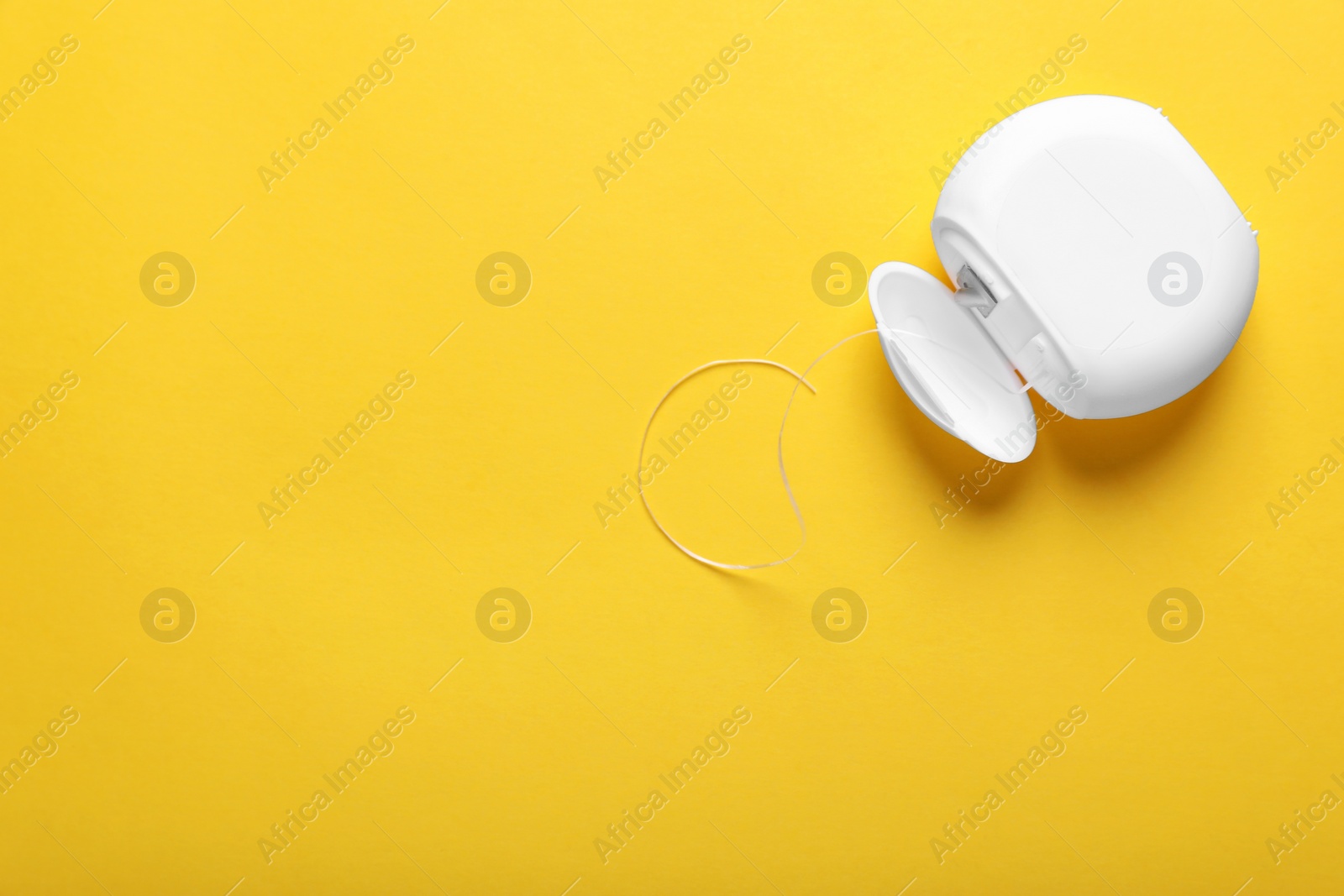 Photo of Container with dental floss on yellow background, top view. Space for text