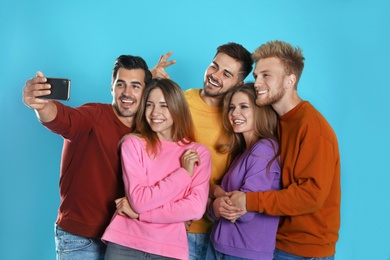 Happy young people taking selfie on blue background