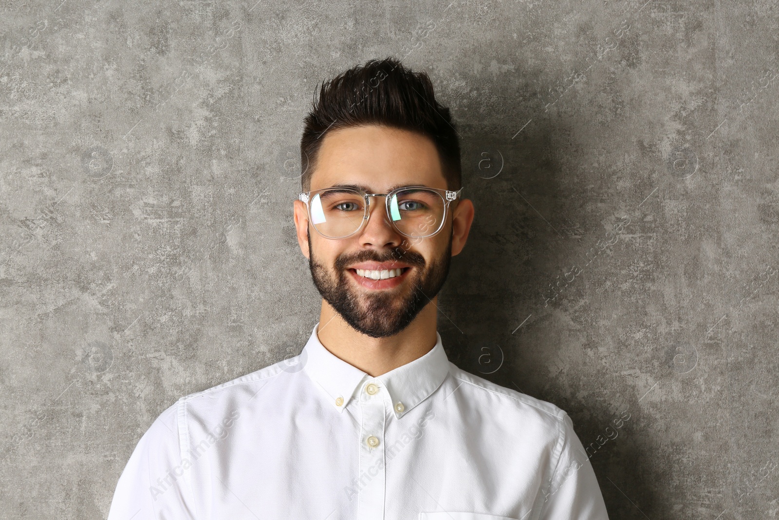 Photo of Portrait of handsome smiling man in glasses on grey background