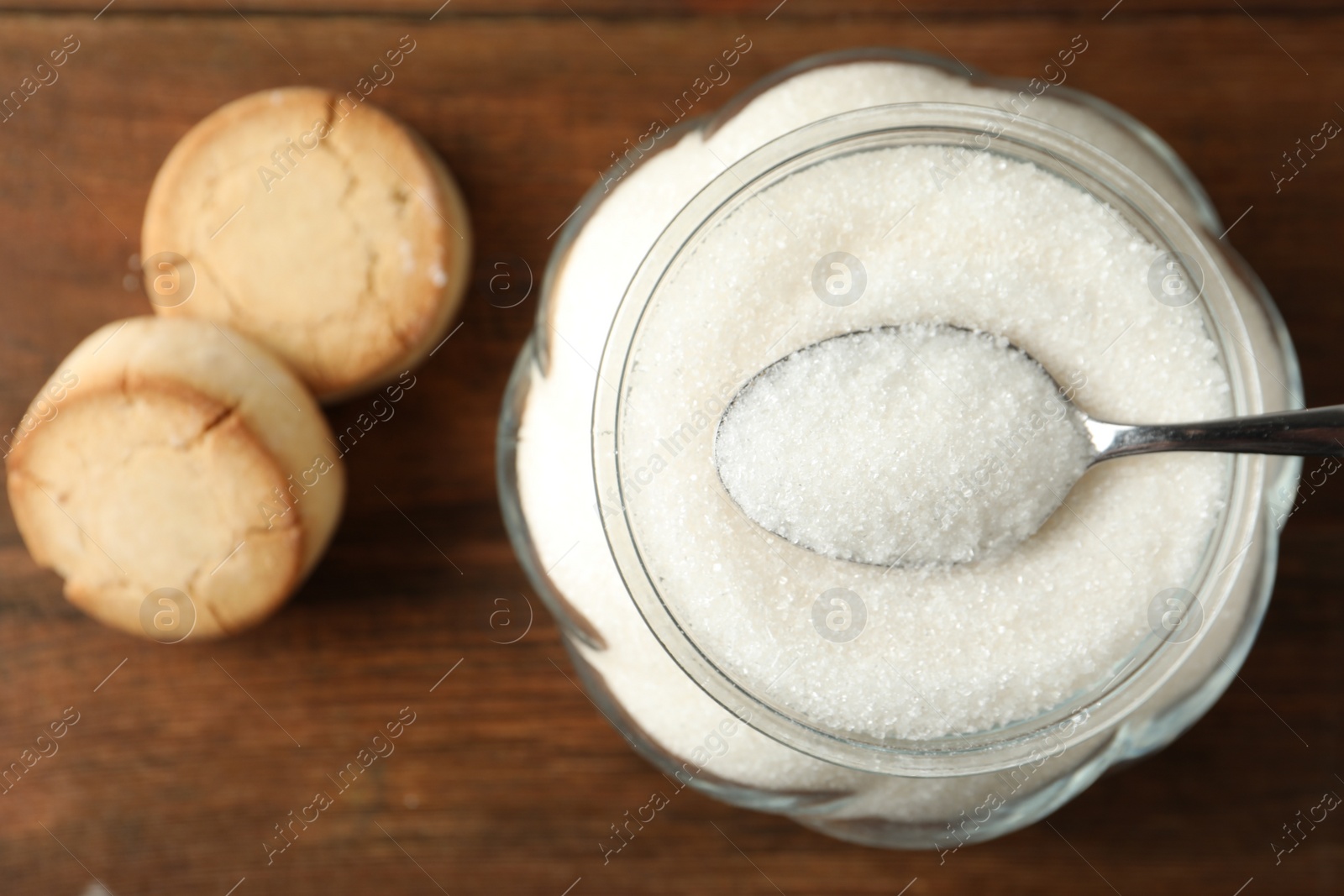 Photo of Glass bowl with sugar and cookies on wooden table, flat lay