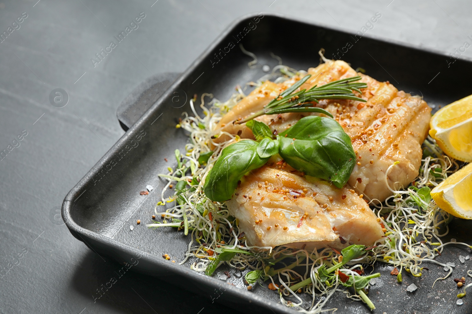 Photo of Tasty grilled fish on black table, closeup