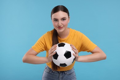 Photo of Beautiful soccer fan with ball on light blue background