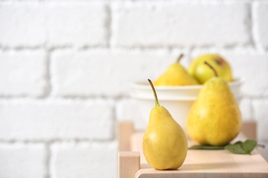 Ripe pear on wooden shelf against blurred background. Space for text