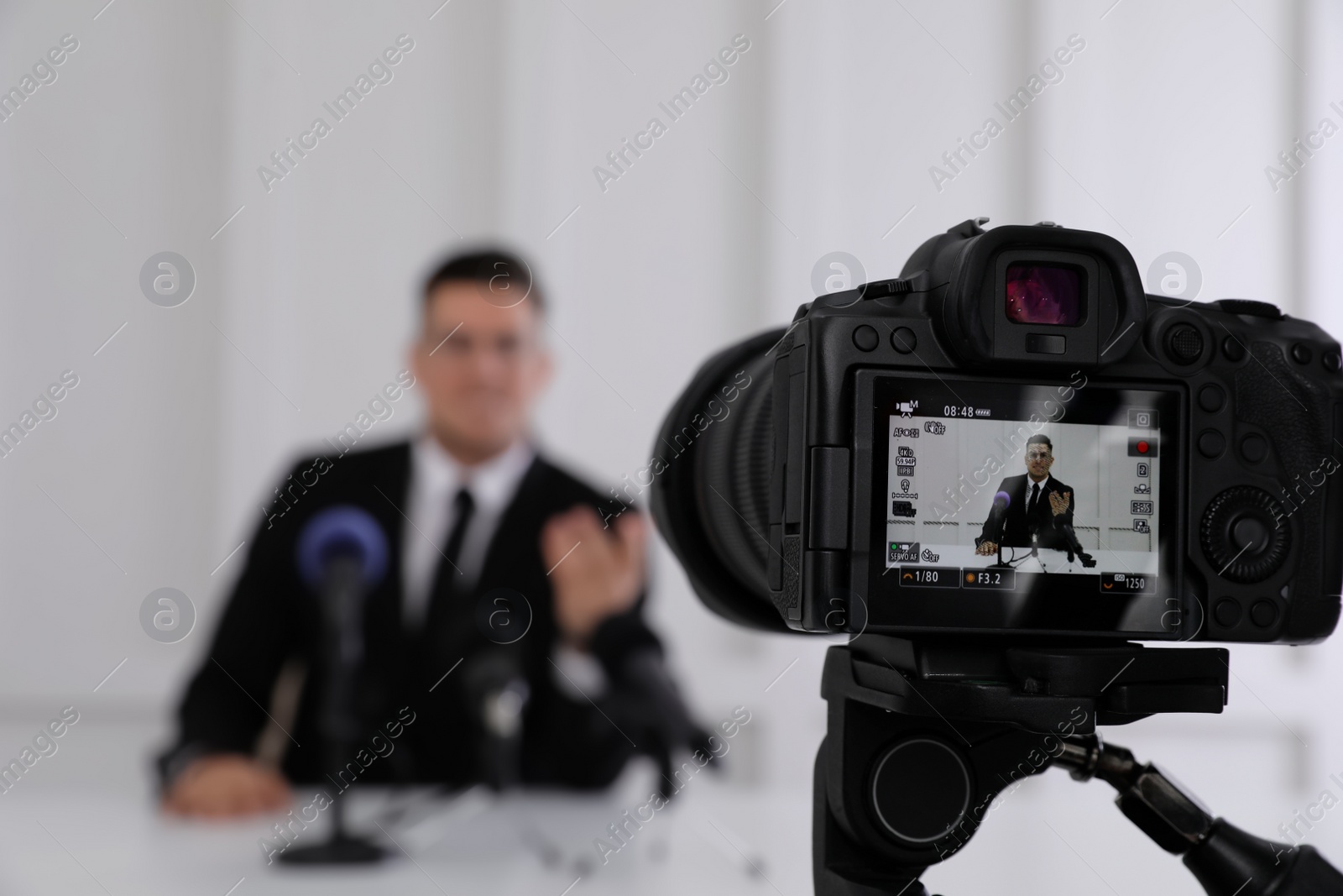 Photo of Business man giving interview at official event, focus on video camera screen