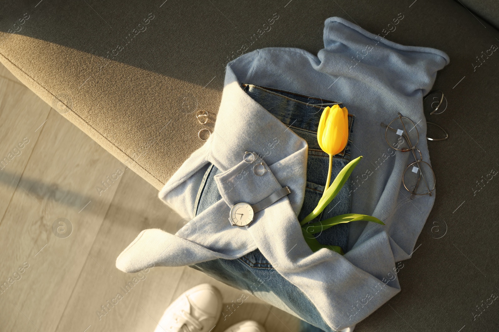 Photo of Soft cashmere sweater, jeans, accessories and tulip on sofa, flat lay