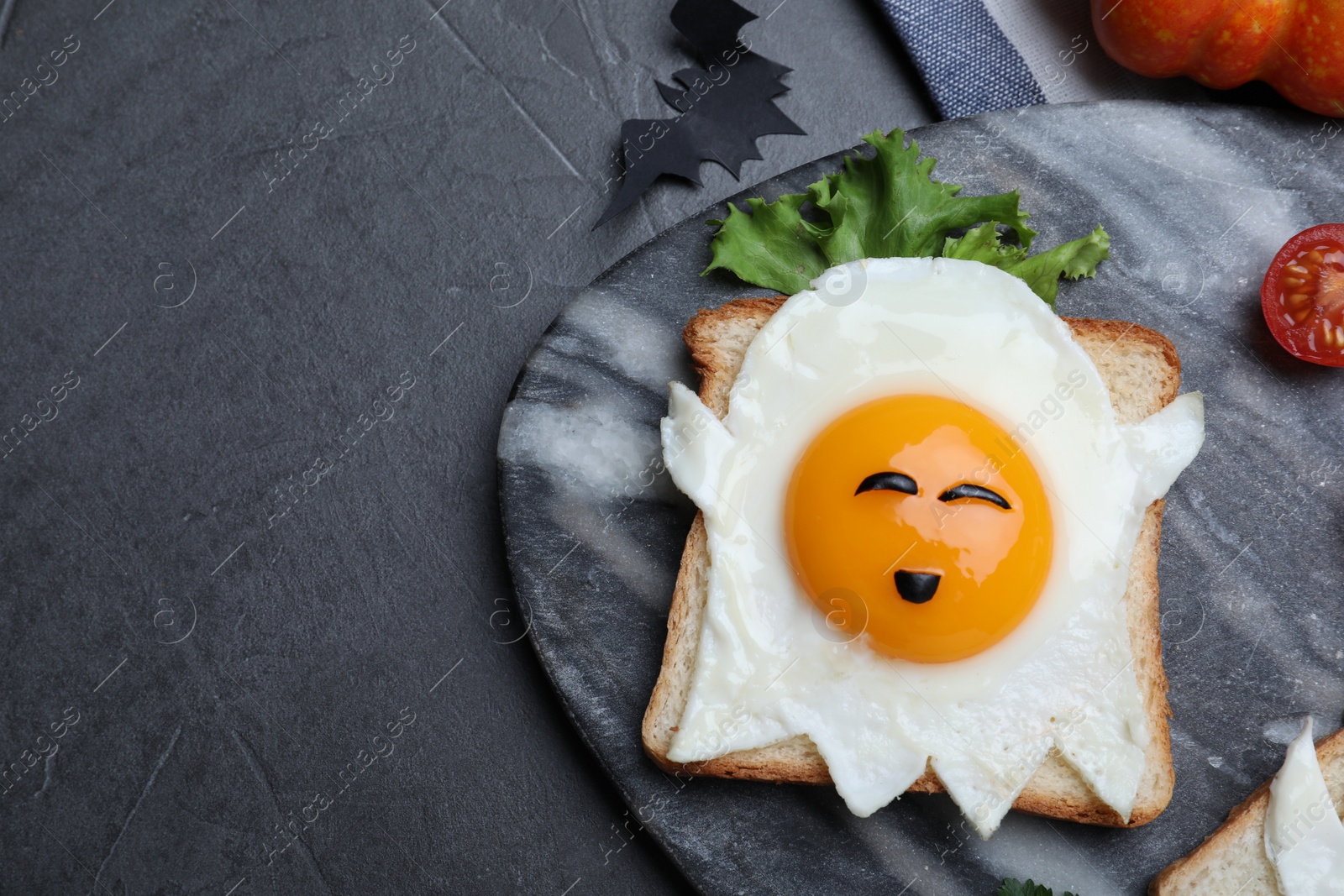 Photo of Halloween themed breakfast served on black table, flat lay and space for text. Tasty toast with fried egg in shape of ghost