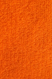 Fluffy orange fabric as background, top view