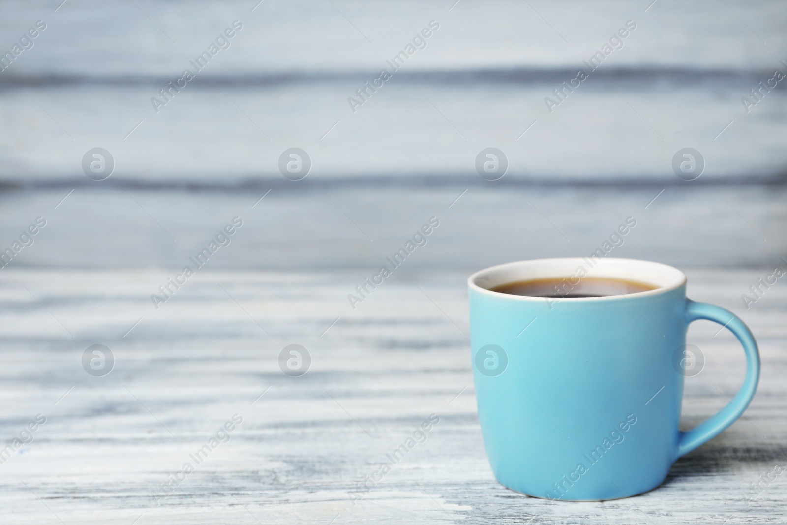 Photo of Blue ceramic cup with hot aromatic coffee on table