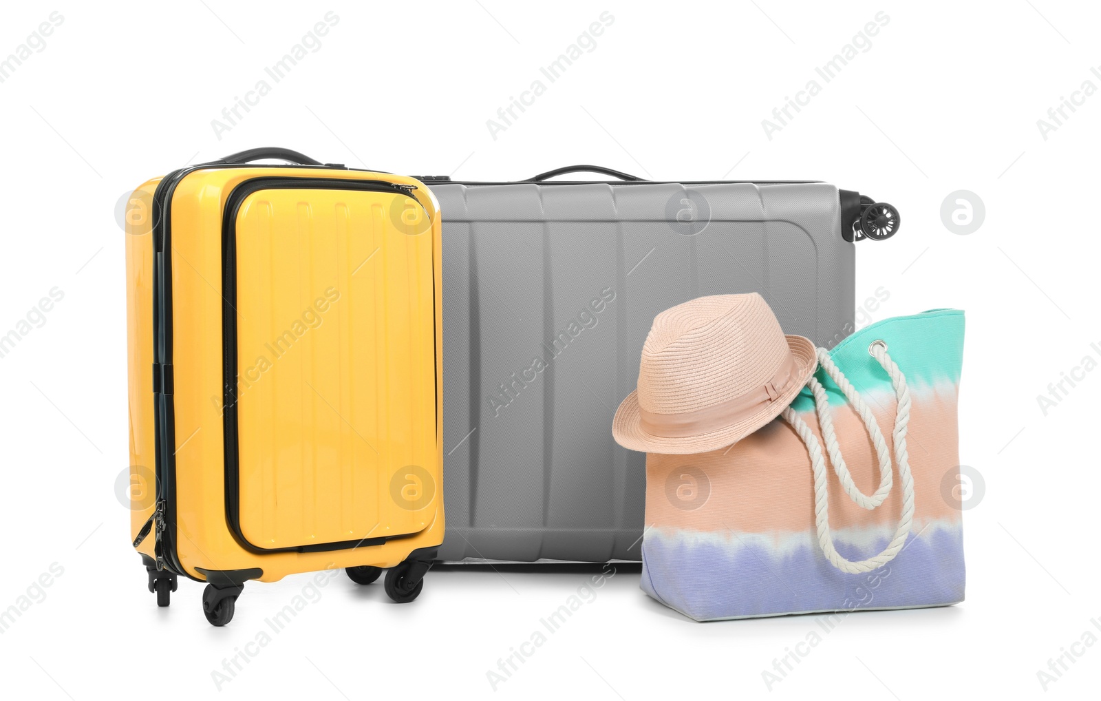 Photo of New suitcases, bag and hat packed for journey on white background