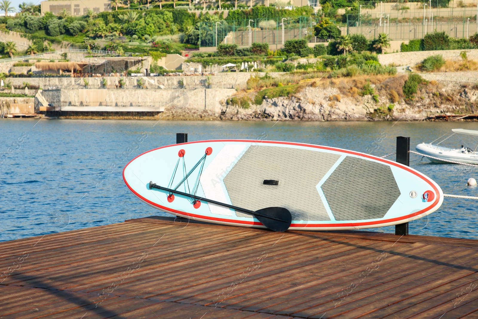 Photo of SUP board with paddle on wooden pier near sea