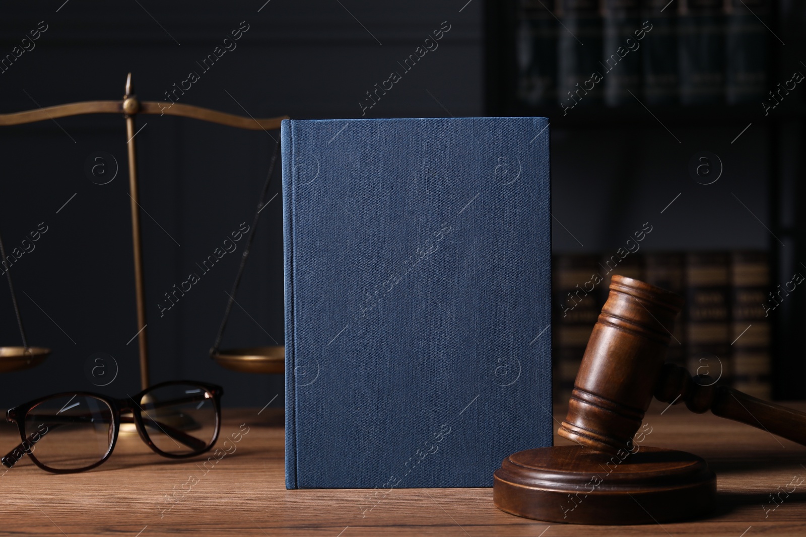 Photo of Law. Book, gavel, scales and glasses on wooden table