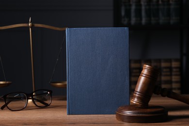 Photo of Law. Book, gavel, scales and glasses on wooden table