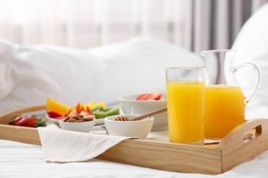Photo of Wooden tray with tasty breakfast on bed at home