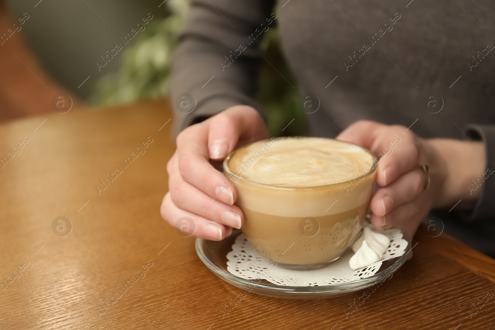 Photo of Young woman with cup of delicious coffee at table