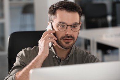 Photo of Man talking on smartphone at workplace in office