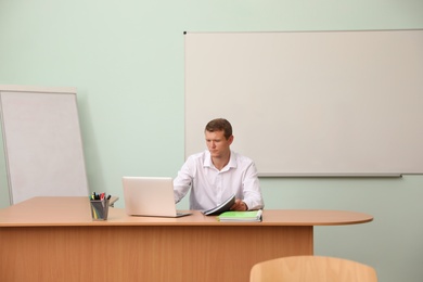 Photo of Male teacher at his desk in classroom