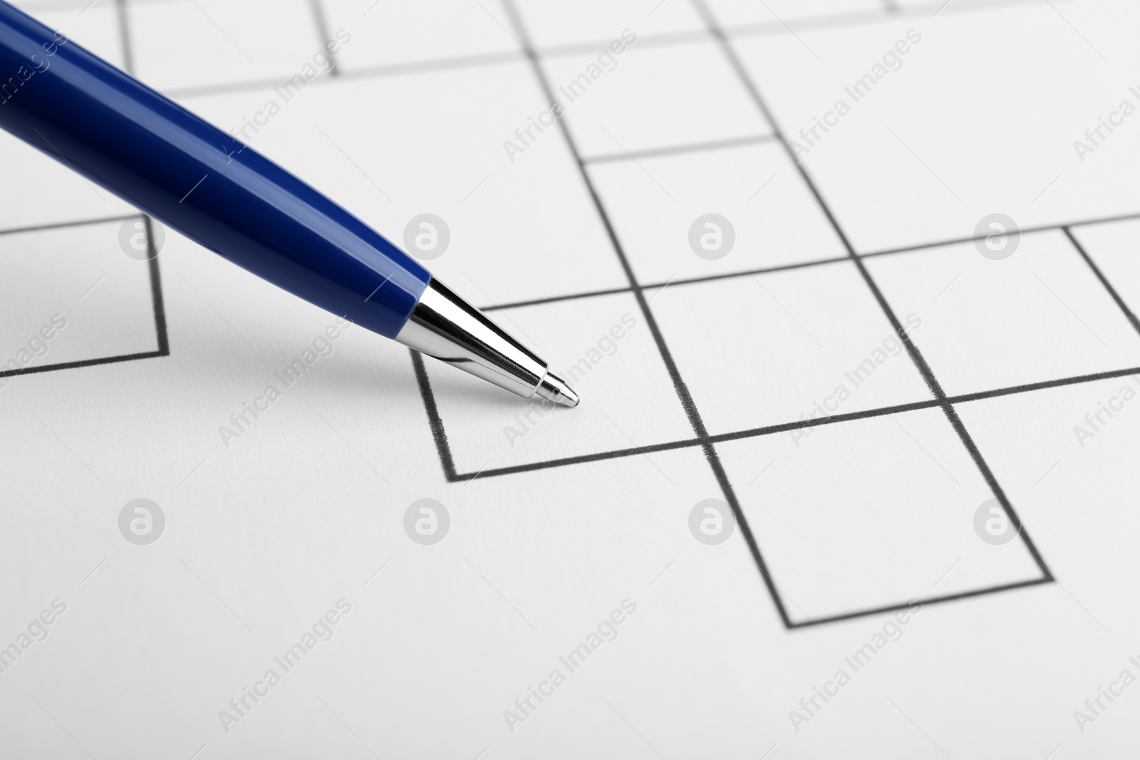 Photo of Pen and blank crossword, closeup. Space for text