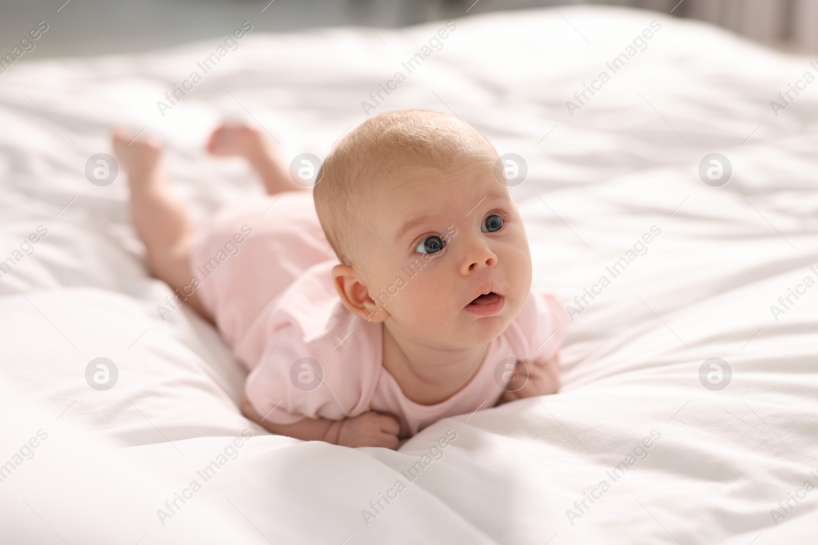 Photo of Cute little baby lying on white sheets