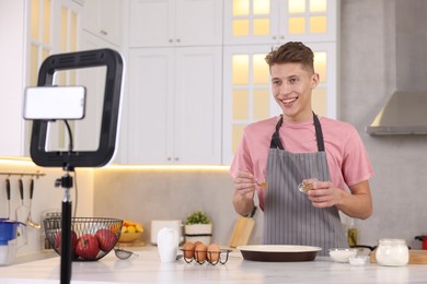 Photo of Smiling food blogger cooking while recording video in kitchen