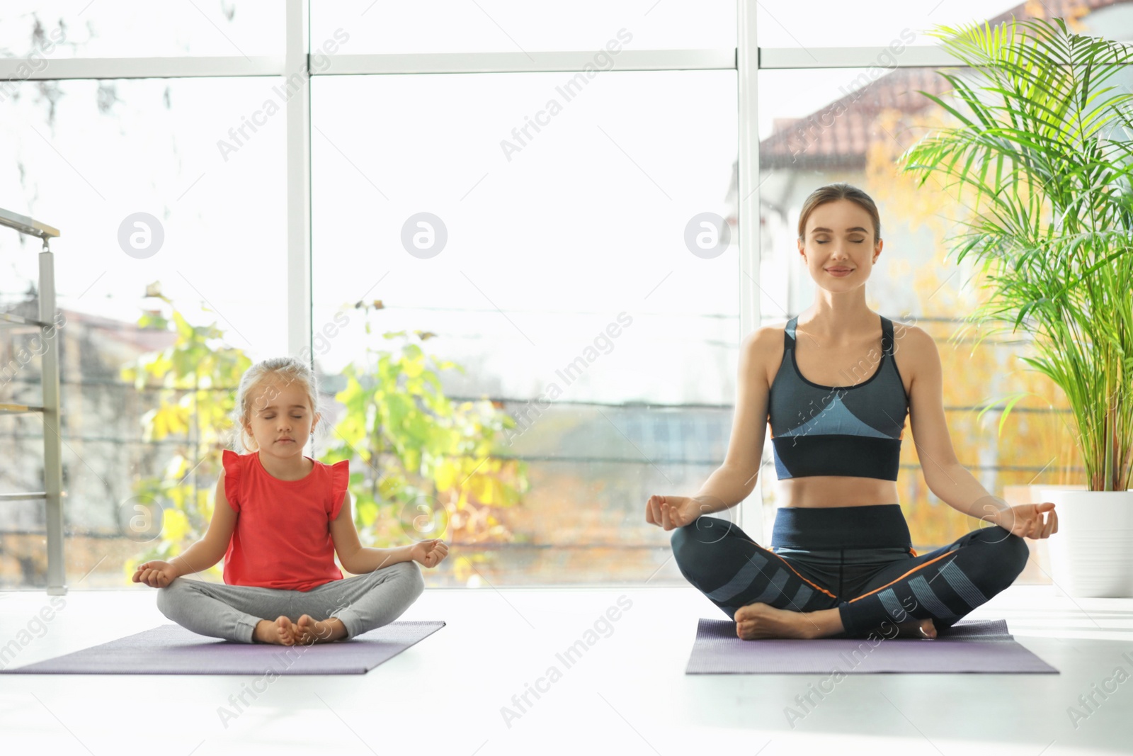 Photo of Young woman and her daughter doing exercise indoors. Home fitness