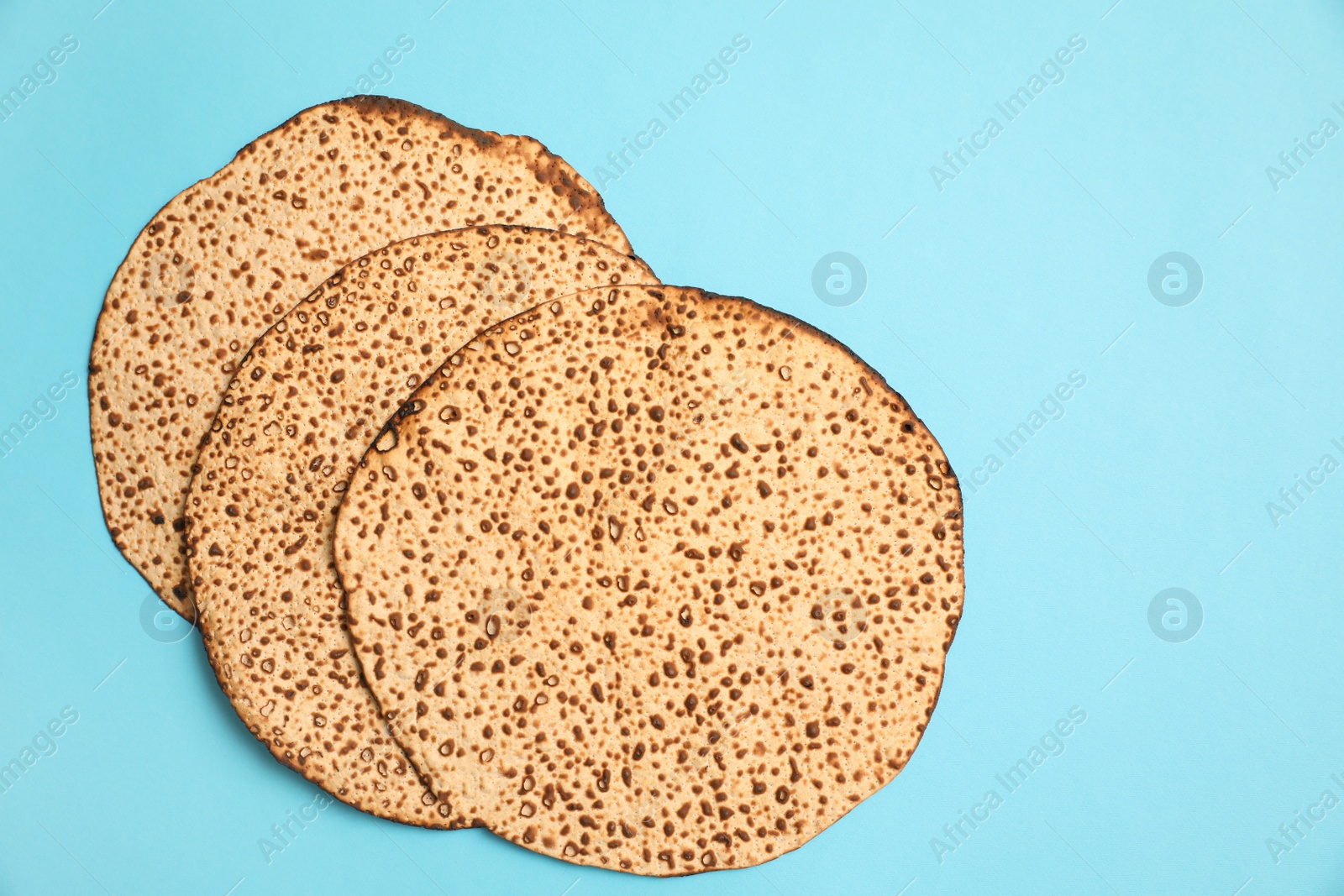 Photo of Tasty matzos on light blue background, flat lay. Passover (Pesach) celebration