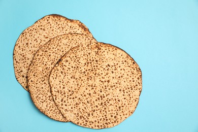 Photo of Tasty matzos on light blue background, flat lay. Passover (Pesach) celebration