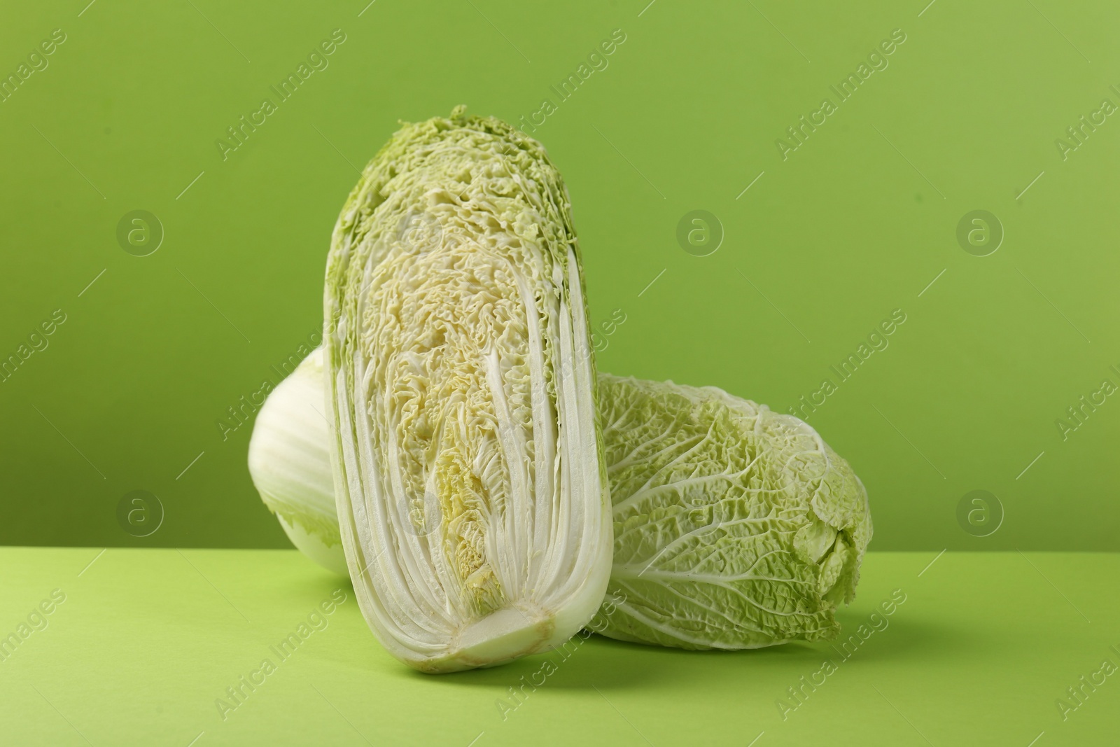 Photo of Whole and cut fresh Chinese cabbage on light green background