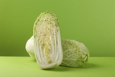 Whole and cut fresh Chinese cabbage on light green background